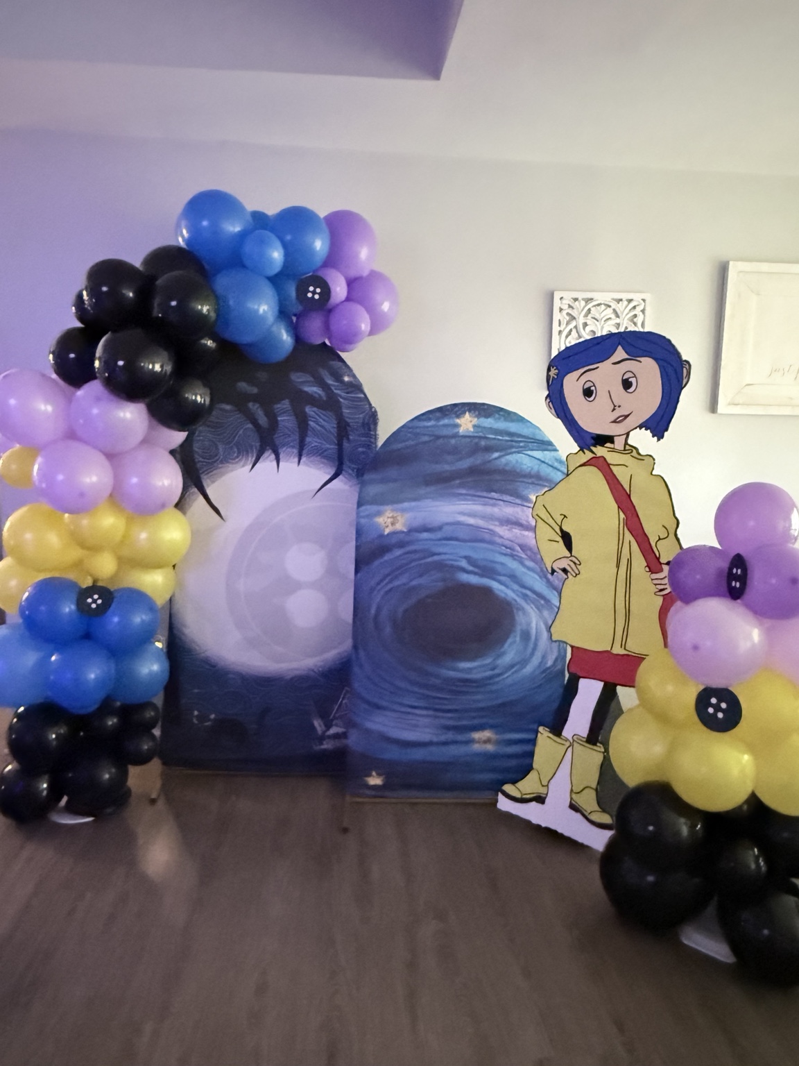 Coraline party backdrop with character cutout and colorful balloon arrangements